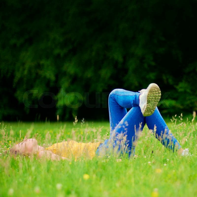 A woman relaxing in a grassy field, enjoying a peaceful moment outdoors away from screens and digital distractions.